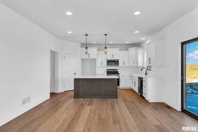 kitchen with pendant lighting, white cabinets, a center island, stainless steel appliances, and light wood-type flooring