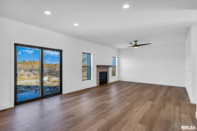 unfurnished living room featuring hardwood / wood-style floors, a tile fireplace, and ceiling fan