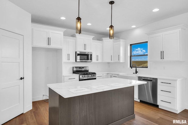 kitchen with sink, white cabinetry, stainless steel appliances, a center island, and decorative light fixtures