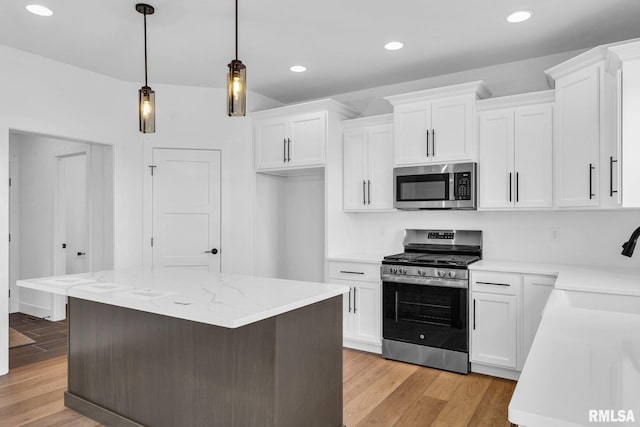 kitchen featuring white cabinetry, light wood-type flooring, a kitchen island, pendant lighting, and stainless steel appliances