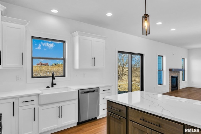 kitchen with white cabinetry, sink, stainless steel dishwasher, and hanging light fixtures