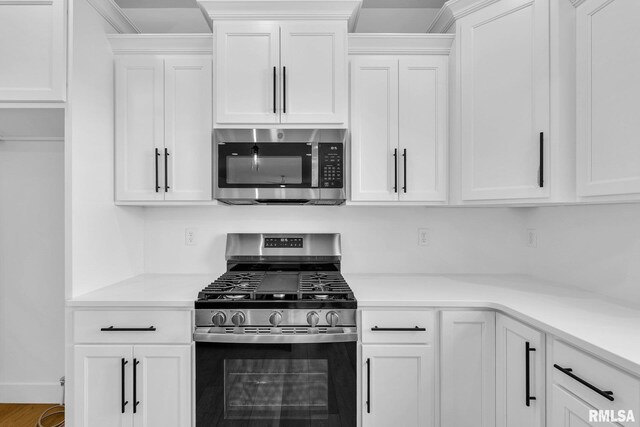 kitchen with hardwood / wood-style flooring, stainless steel appliances, and white cabinets