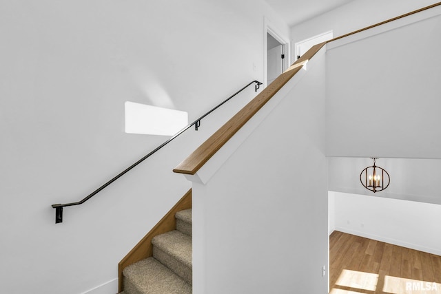 staircase with hardwood / wood-style floors and a chandelier