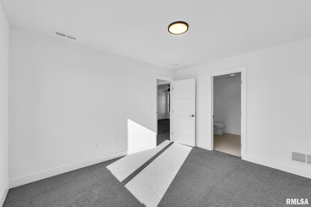 unfurnished bedroom featuring connected bathroom and dark carpet