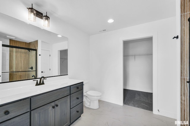 bathroom featuring vanity, a shower with shower door, and toilet