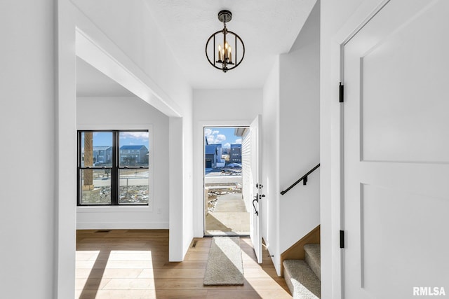 foyer entrance featuring light wood-type flooring and an inviting chandelier