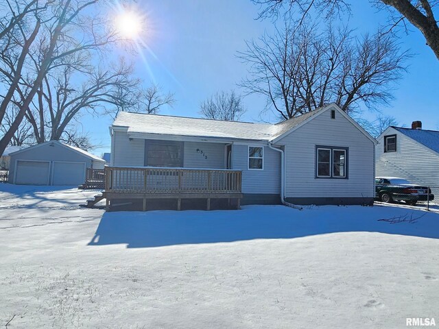 snow covered house featuring a garage, an outbuilding, and covered porch