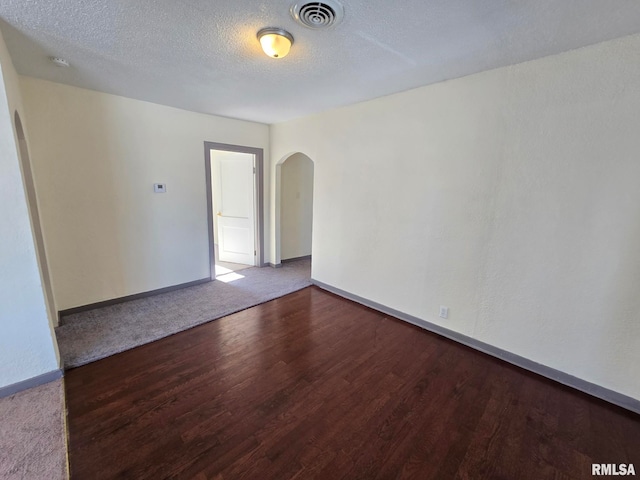 spare room featuring wood-type flooring and a textured ceiling