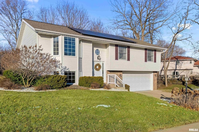 raised ranch with a front yard, a garage, and solar panels