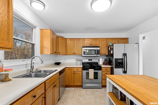 kitchen with sink, light tile patterned floors, and stainless steel appliances