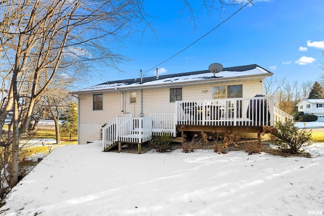 snow covered rear of property with a wooden deck