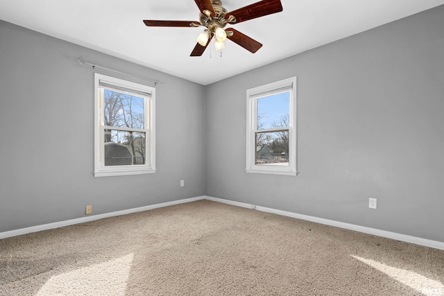 carpeted spare room featuring ceiling fan and plenty of natural light