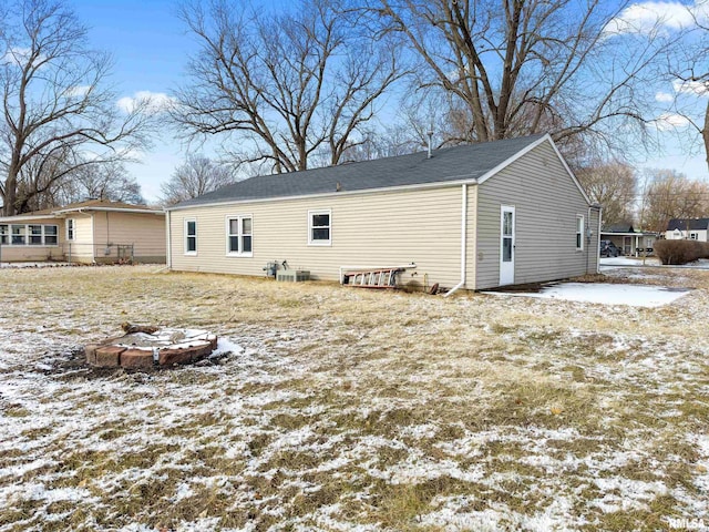 snow covered rear of property with central air condition unit and an outdoor fire pit