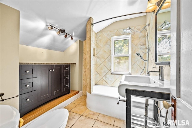 full bathroom featuring toilet, vanity, vaulted ceiling, tiled shower / bath, and tile patterned floors