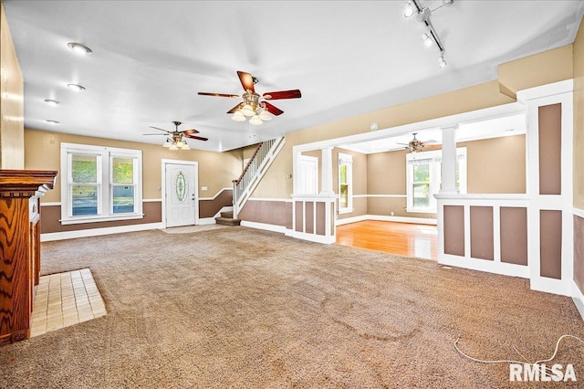 unfurnished living room with decorative columns, light colored carpet, and track lighting