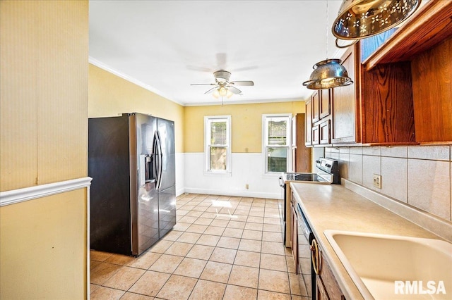 kitchen featuring decorative light fixtures, stainless steel appliances, sink, light tile patterned floors, and crown molding