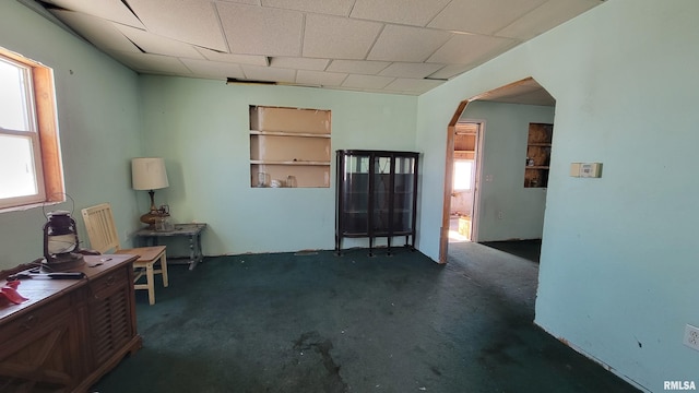 interior space featuring dark carpet, built in features, and plenty of natural light