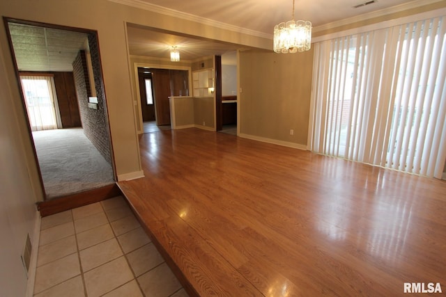 unfurnished room with light wood-type flooring, an inviting chandelier, and ornamental molding