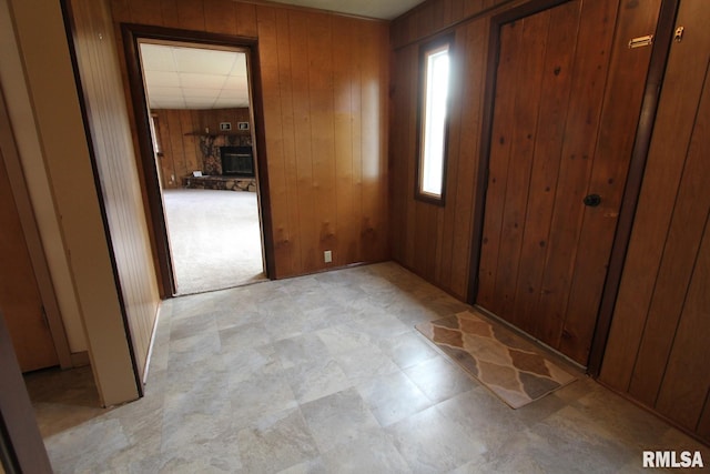 foyer with a stone fireplace and wooden walls