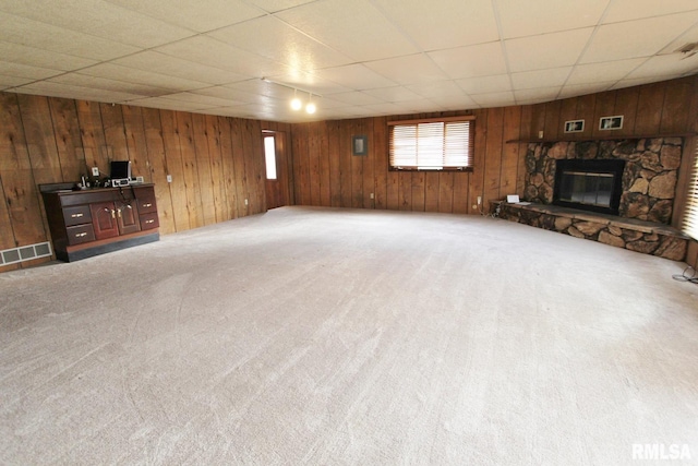 unfurnished living room with a paneled ceiling, carpet flooring, and a stone fireplace