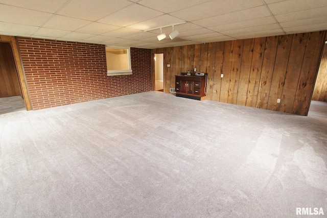 basement with brick wall, wooden walls, and carpet flooring