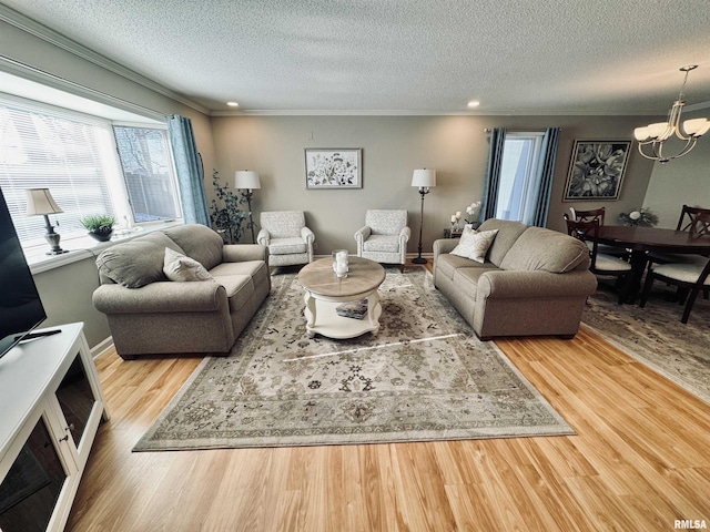 living room with a textured ceiling, an inviting chandelier, crown molding, and light hardwood / wood-style flooring