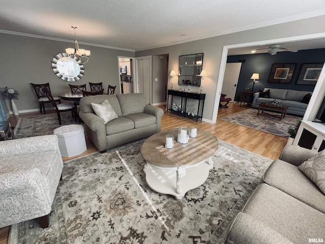 living room with a textured ceiling, ornamental molding, ceiling fan with notable chandelier, and hardwood / wood-style floors