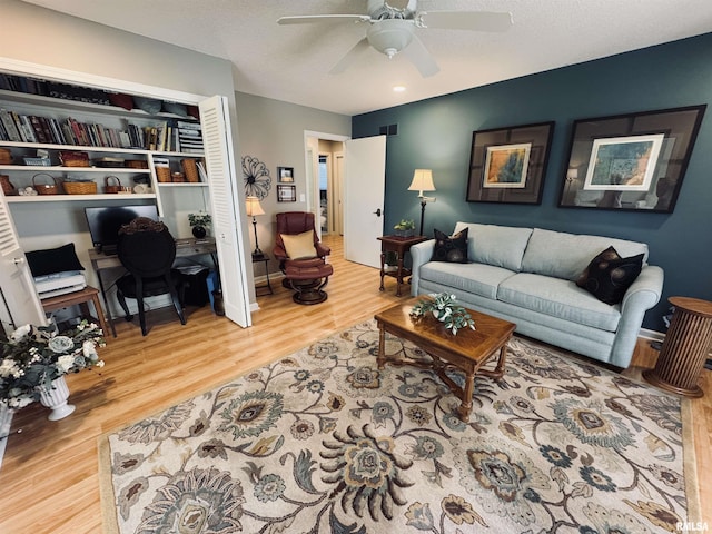 living room featuring a textured ceiling, ceiling fan, built in features, and wood-type flooring