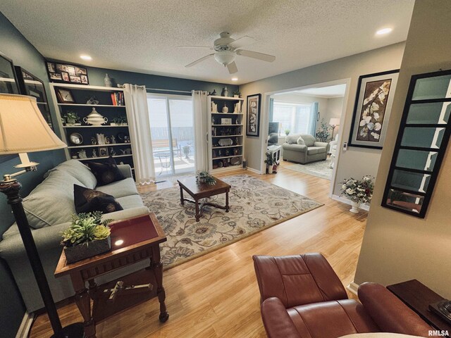 living room featuring ceiling fan, wood-type flooring, and a textured ceiling