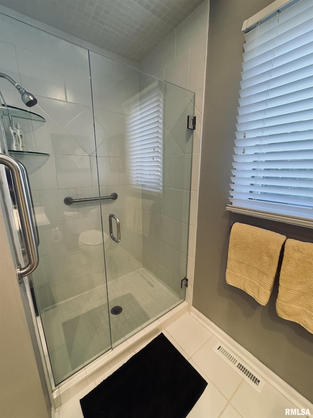 bathroom with a shower with shower door and tile patterned flooring