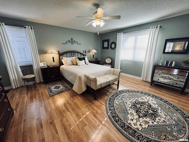 bedroom with a textured ceiling, ceiling fan, and hardwood / wood-style floors