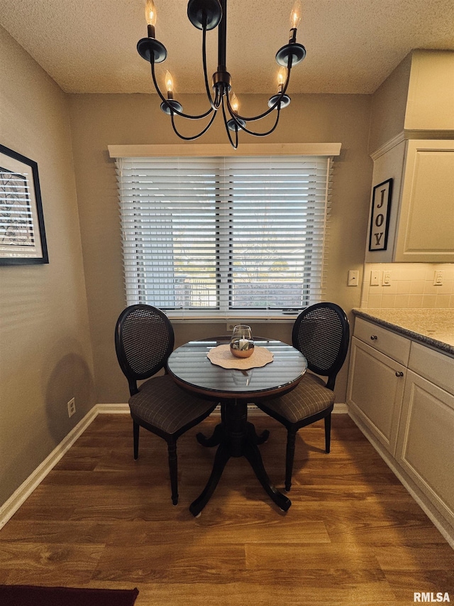 dining area with a textured ceiling, hardwood / wood-style flooring, and a notable chandelier