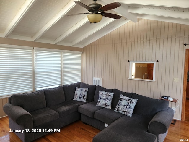 living room featuring lofted ceiling with beams, ceiling fan, wooden walls, and hardwood / wood-style floors