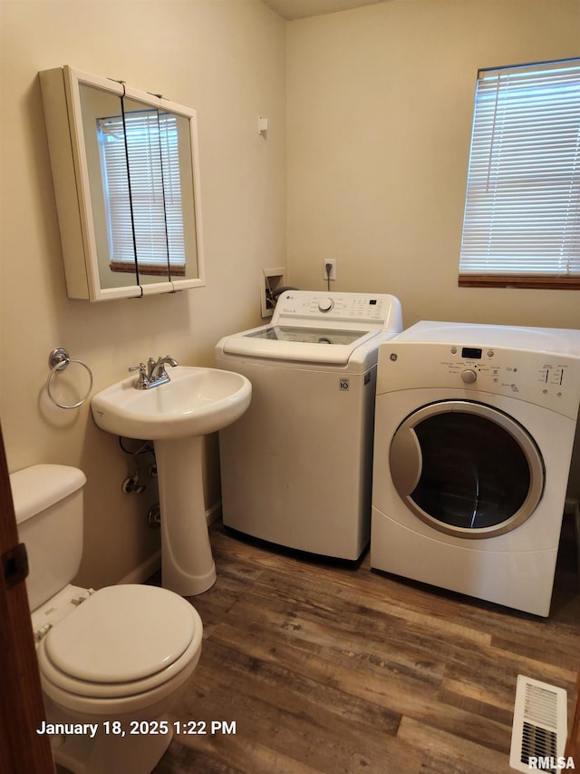 laundry area with dark hardwood / wood-style floors, sink, and washing machine and clothes dryer