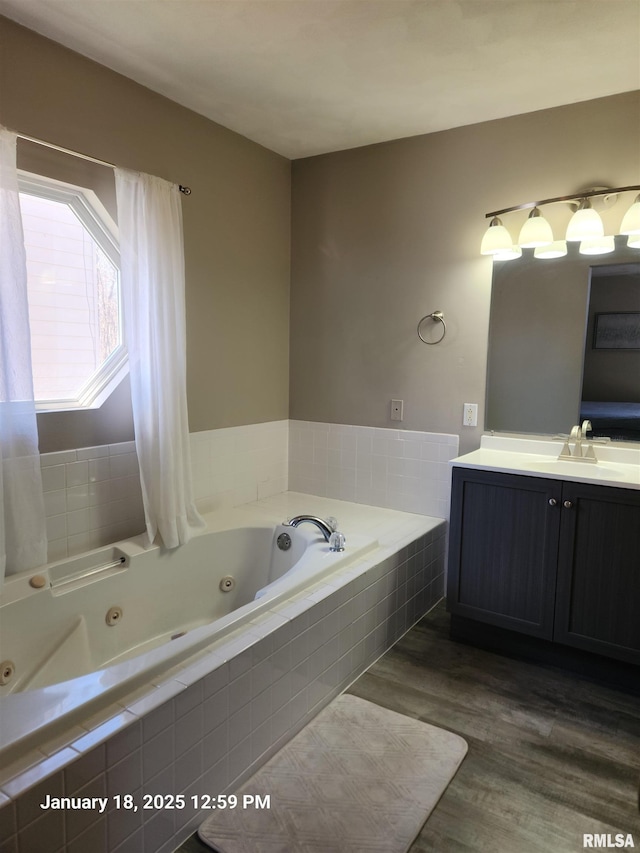 bathroom featuring hardwood / wood-style flooring, vanity, and tiled bath