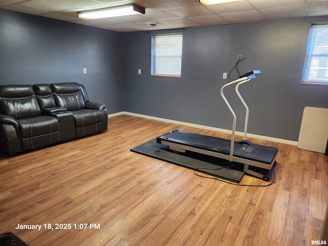 exercise room with a healthy amount of sunlight, a drop ceiling, and light wood-type flooring