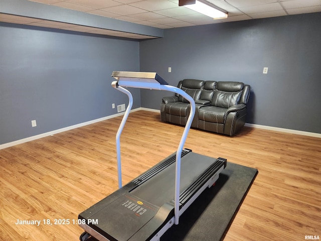 workout area featuring wood-type flooring and a drop ceiling