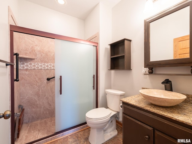 bathroom featuring toilet, a shower with door, and vanity