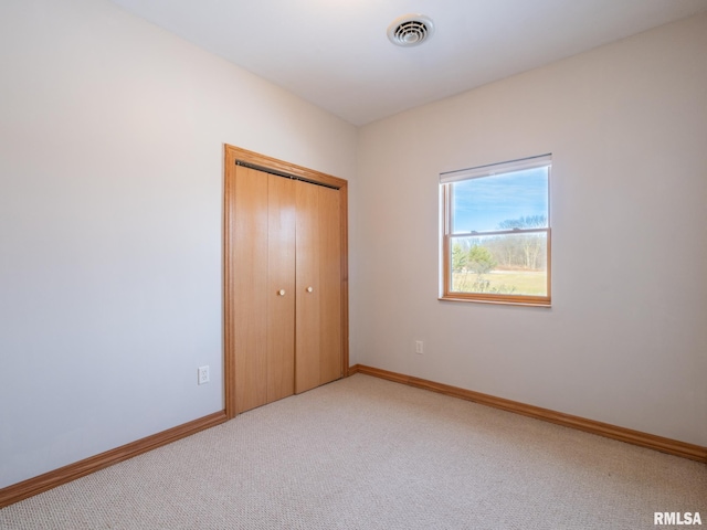 unfurnished bedroom with light carpet and a closet