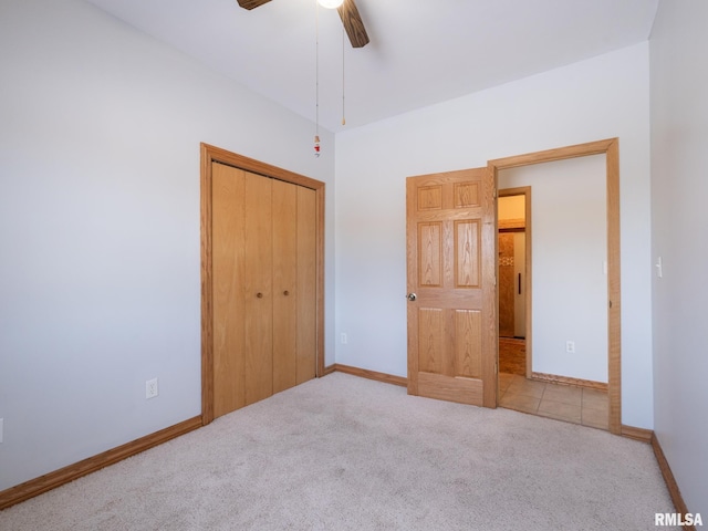 unfurnished bedroom featuring ceiling fan, a closet, and light colored carpet