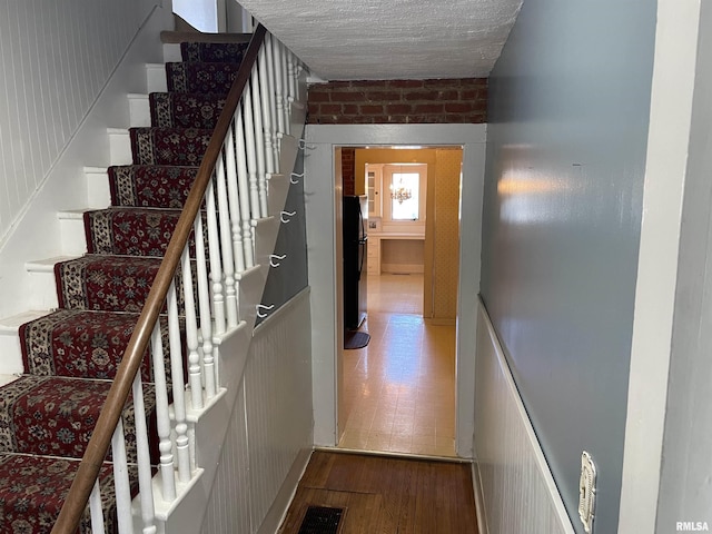 staircase with brick wall and hardwood / wood-style flooring