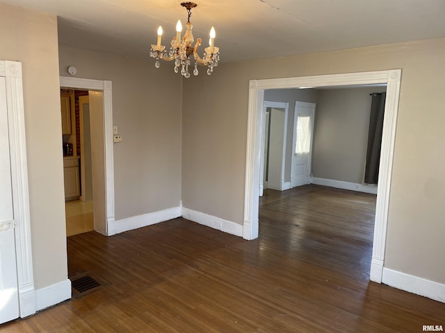 unfurnished room featuring dark hardwood / wood-style floors and a notable chandelier