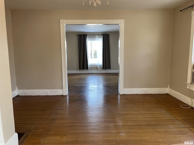 unfurnished room with wood-type flooring and a notable chandelier