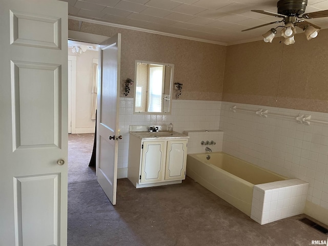 bathroom with ceiling fan, a tub to relax in, tile walls, ornamental molding, and vanity