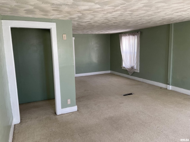 empty room featuring light colored carpet and a textured ceiling