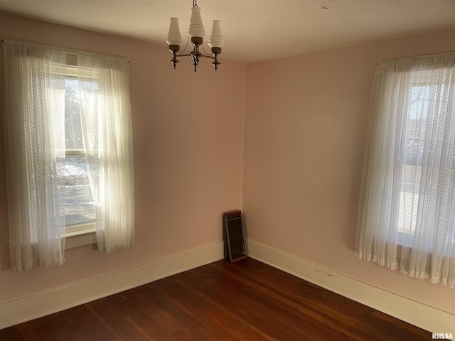 unfurnished room featuring dark hardwood / wood-style floors and an inviting chandelier