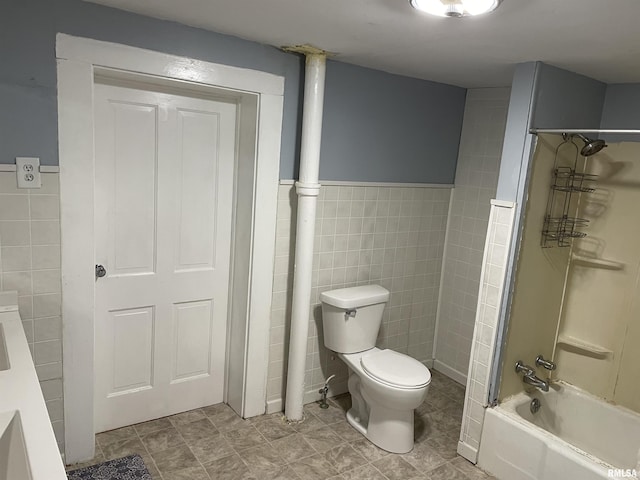 bathroom with toilet, shower / bathtub combination, and tile walls