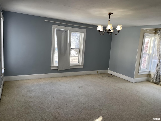 empty room featuring light carpet and a notable chandelier