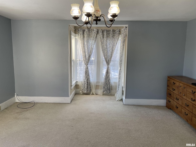 carpeted empty room featuring an inviting chandelier