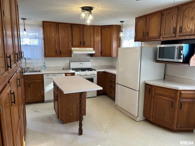 kitchen with decorative light fixtures, sink, a center island, and white appliances